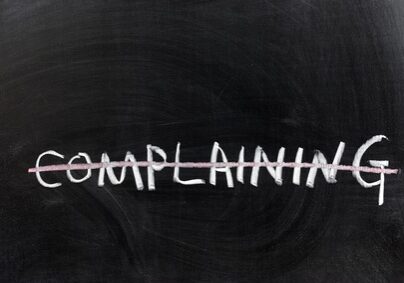 Word "Complaining" On a Chalkboard Crossed out